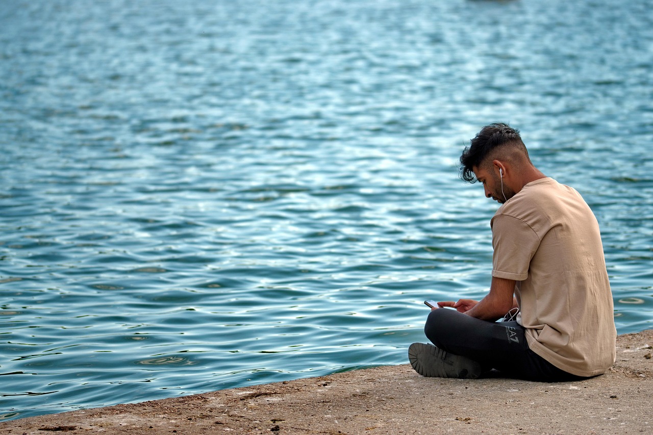 boy the person young placed the shores of the lake listening to the nature the music the headphones your ears phone relaxation the water the nature spring park android