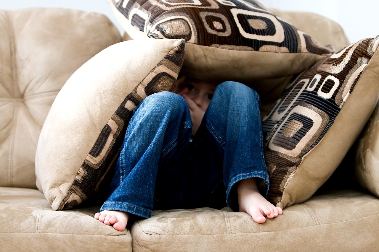 little boy hiding sad child fear pillows couch pillow fort bare feet hide hide and seek brown fear brown couch sad fear fear fear fear fear